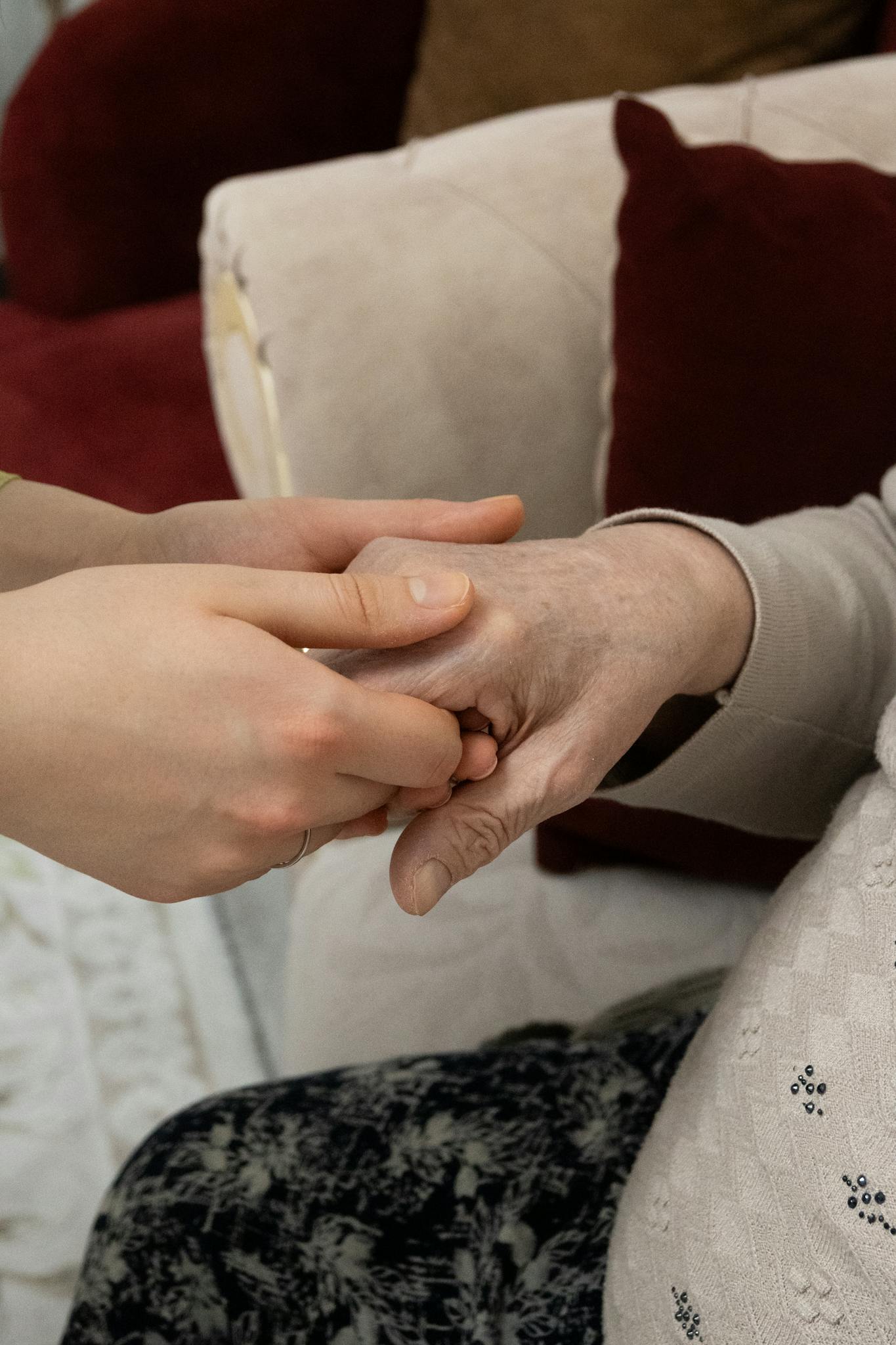 A close-up of two hands showing support and care, symbolizing generational connection indoors.